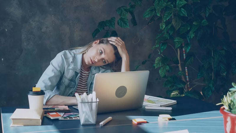Tired worker resting her head in her hand at a laptop