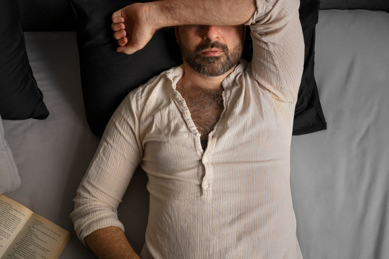 Exhausted man lying down with his arm over his face