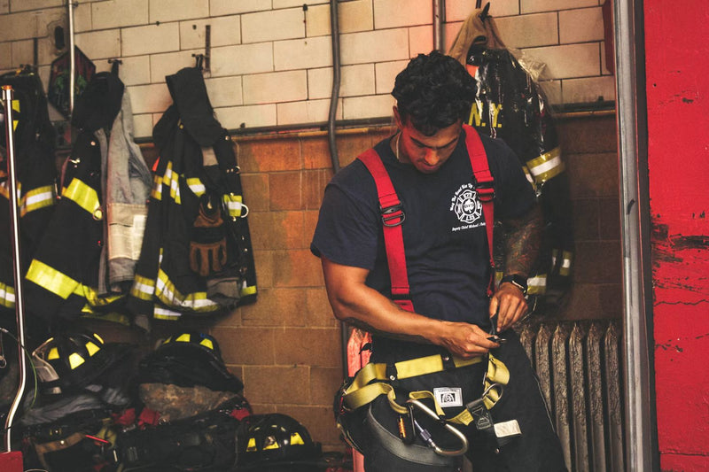 Firefighter adjusting turnout gear in a station locker room