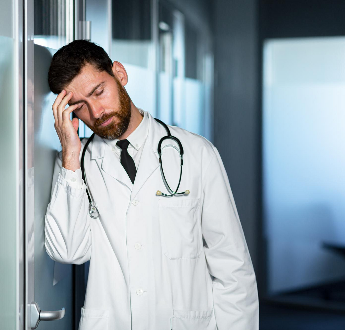 Man in navy scrubs leaning on the kitchen counter, checking his phone after a shift